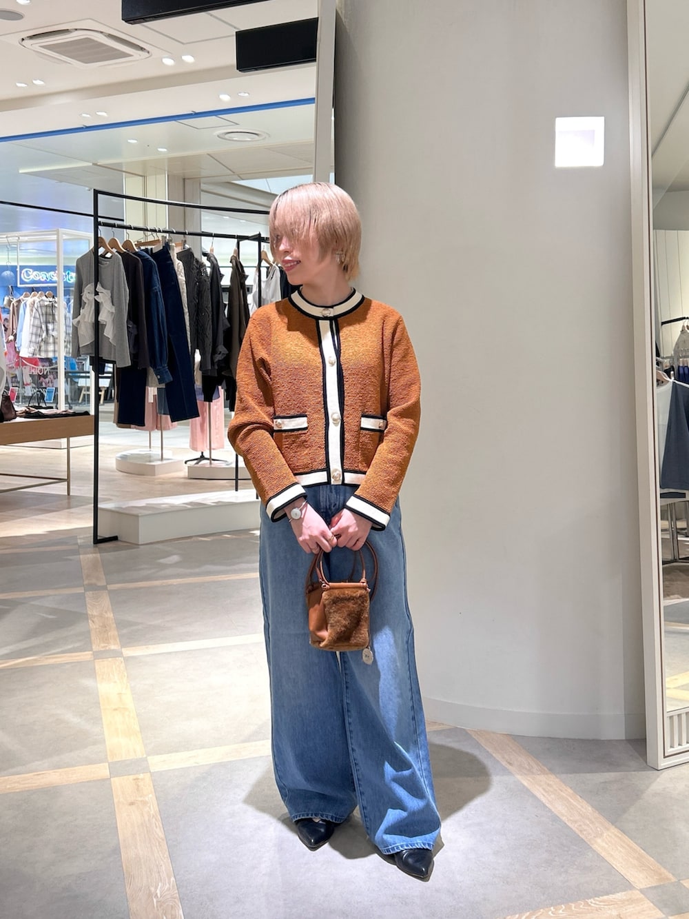 イエロー系のカーディガン/ボレロ、ブルー系のデニムパンツ、イエロー系のショルダーバッグを着用したレディースの秋コーディネートの6枚目の写真