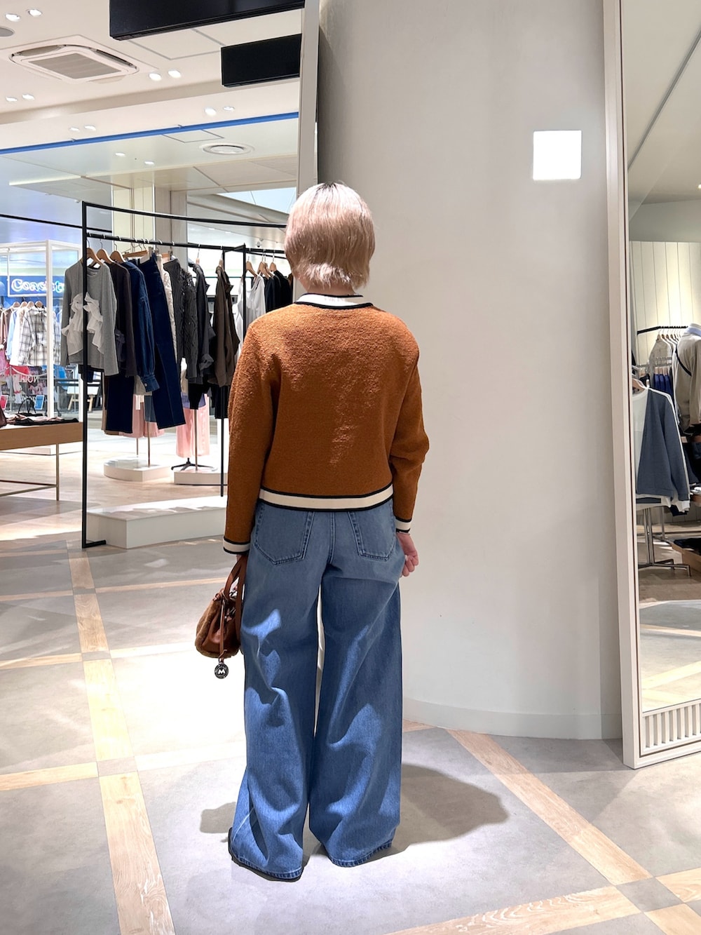 イエロー系のカーディガン/ボレロ、ブルー系のデニムパンツ、イエロー系のショルダーバッグを着用したレディースの秋コーディネートの5枚目の写真