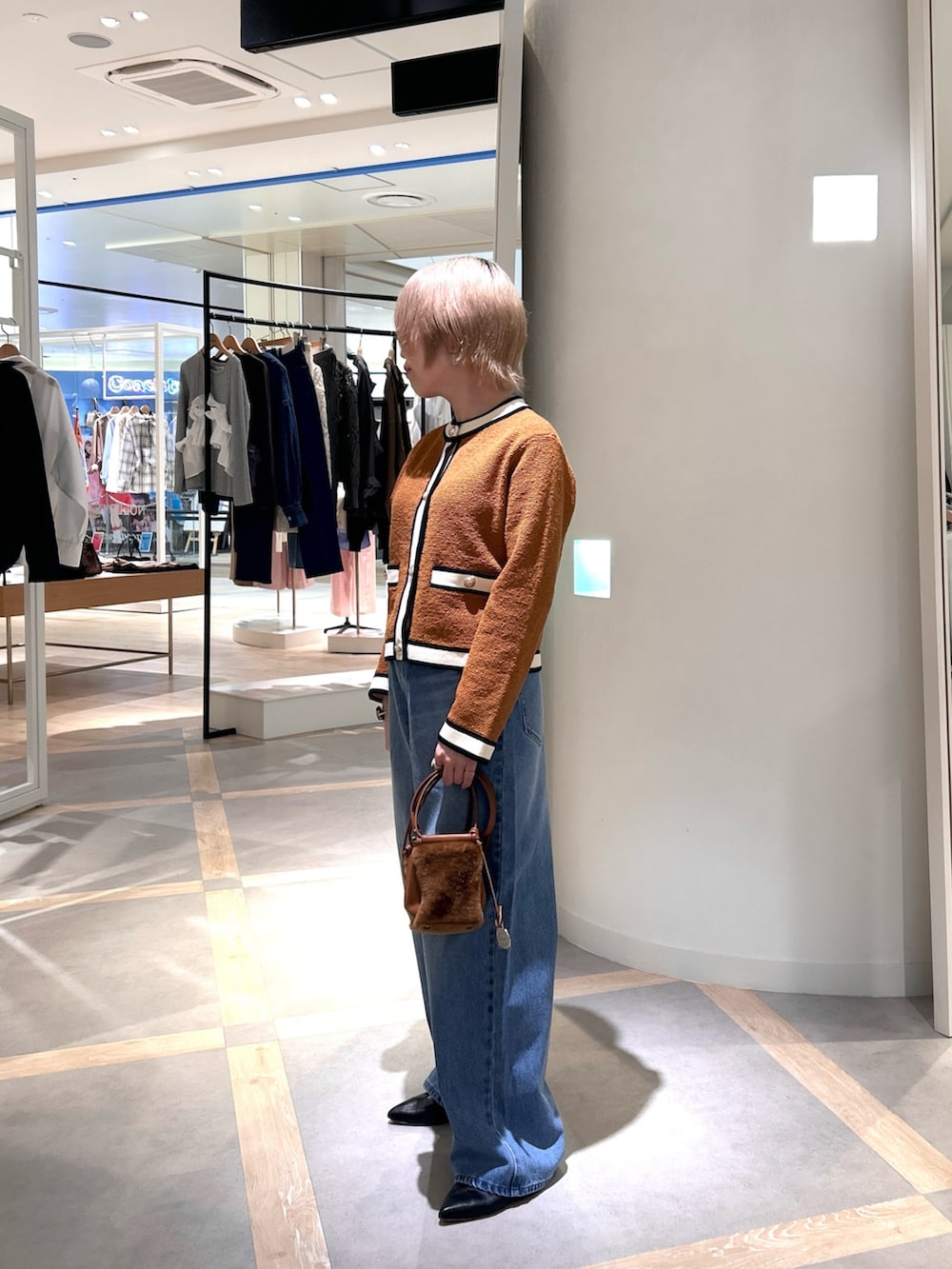 イエロー系のカーディガン/ボレロ、ブルー系のデニムパンツ、イエロー系のショルダーバッグを着用したレディースの秋コーディネートの4枚目の写真