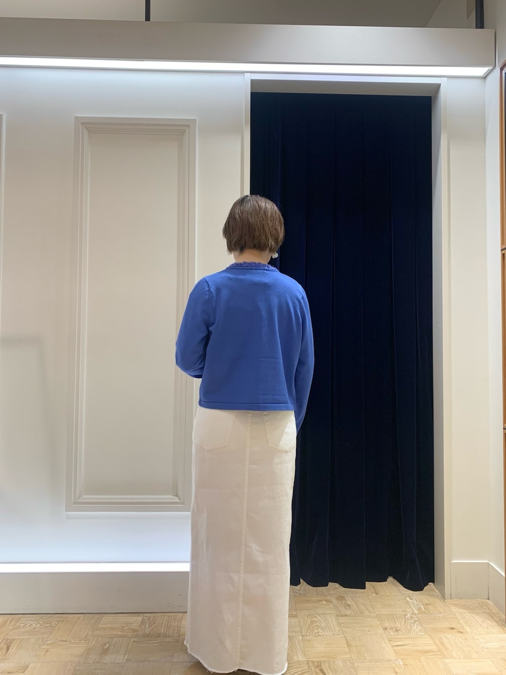 ホワイト系のTシャツ/カットソー、ブルー系のカーディガン/ボレロ、ホワイト系のデニムスカートを着用したレディースの春コーディネートの4枚目の写真