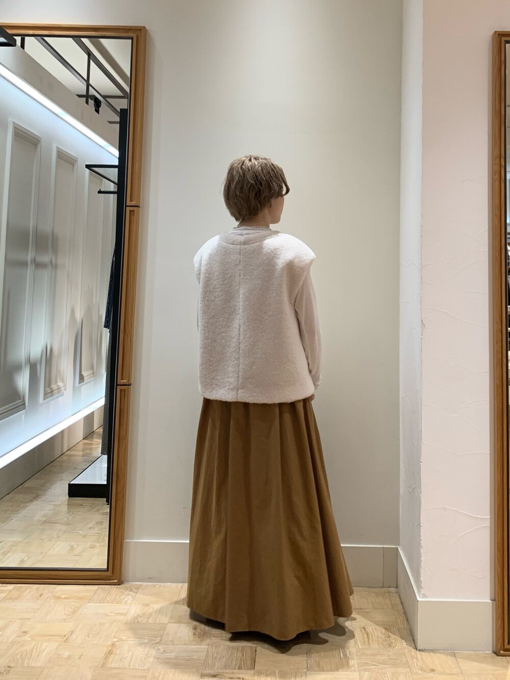 ホワイト系のベスト、ホワイト系のTシャツ/カットソー、イエロー系のスカートを着用したレディースの秋コーディネートの4枚目の写真