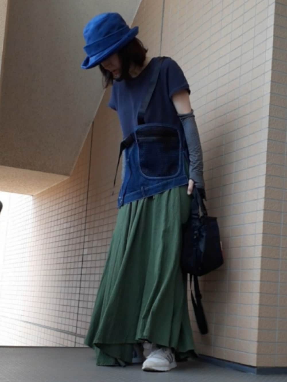 ブルー系のタンクトップ、ブラック系のショルダーバッグ、ホワイト系のスニーカーを着用したレディースの夏コーディネートの2枚目の写真