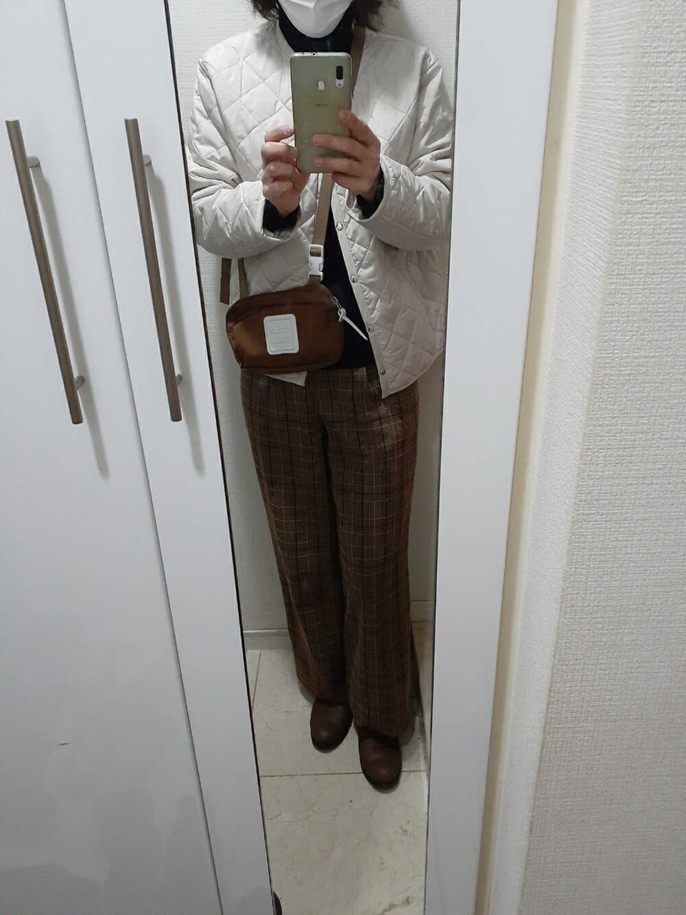 ブラウン系のその他パンツ、ブラウン系のバッグ、ホワイト系のノーカラージャケットを着用したレディースの冬コーディネートの3枚目の写真