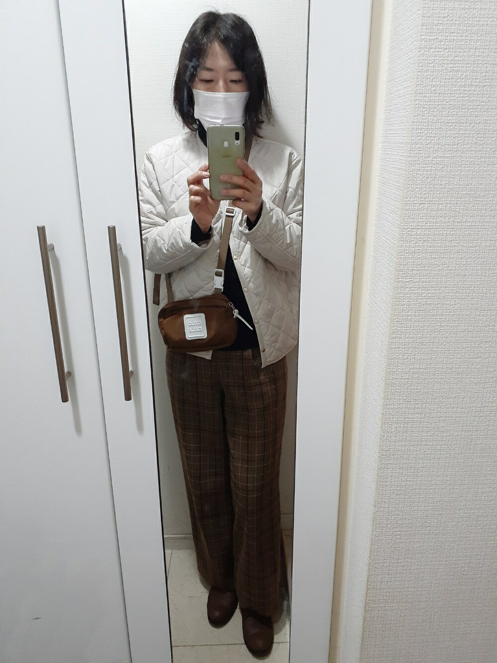 ブラウン系のその他パンツ、ブラウン系のバッグ、ホワイト系のノーカラージャケットを着用したレディースの冬コーディネートの2枚目の写真