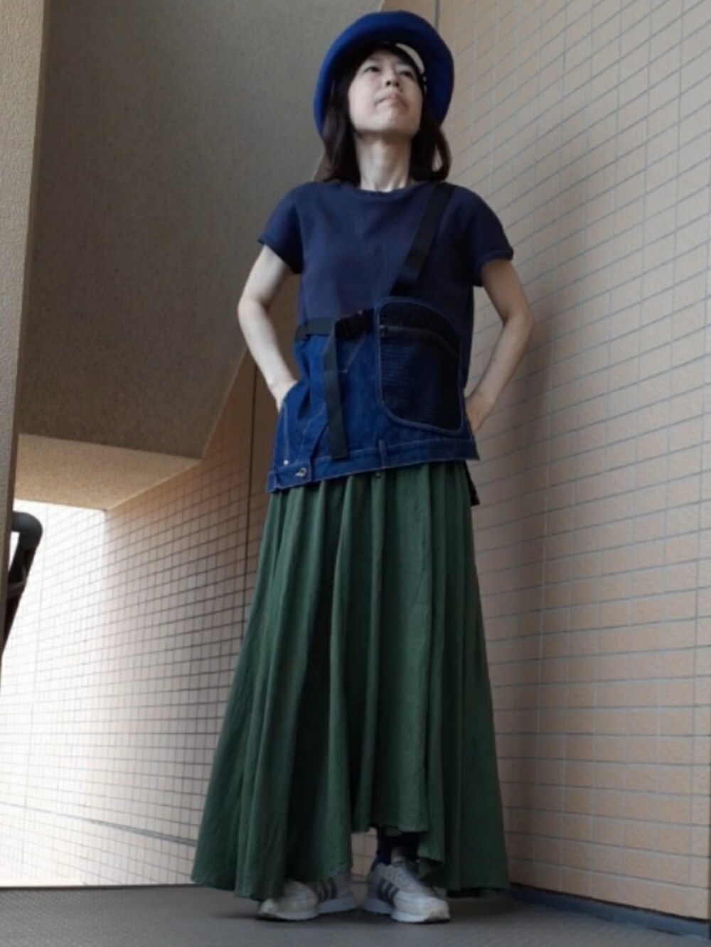 ブルー系のタンクトップ、ブラック系のショルダーバッグ、ホワイト系のスニーカーを着用したレディースの夏コーディネートの4枚目の写真