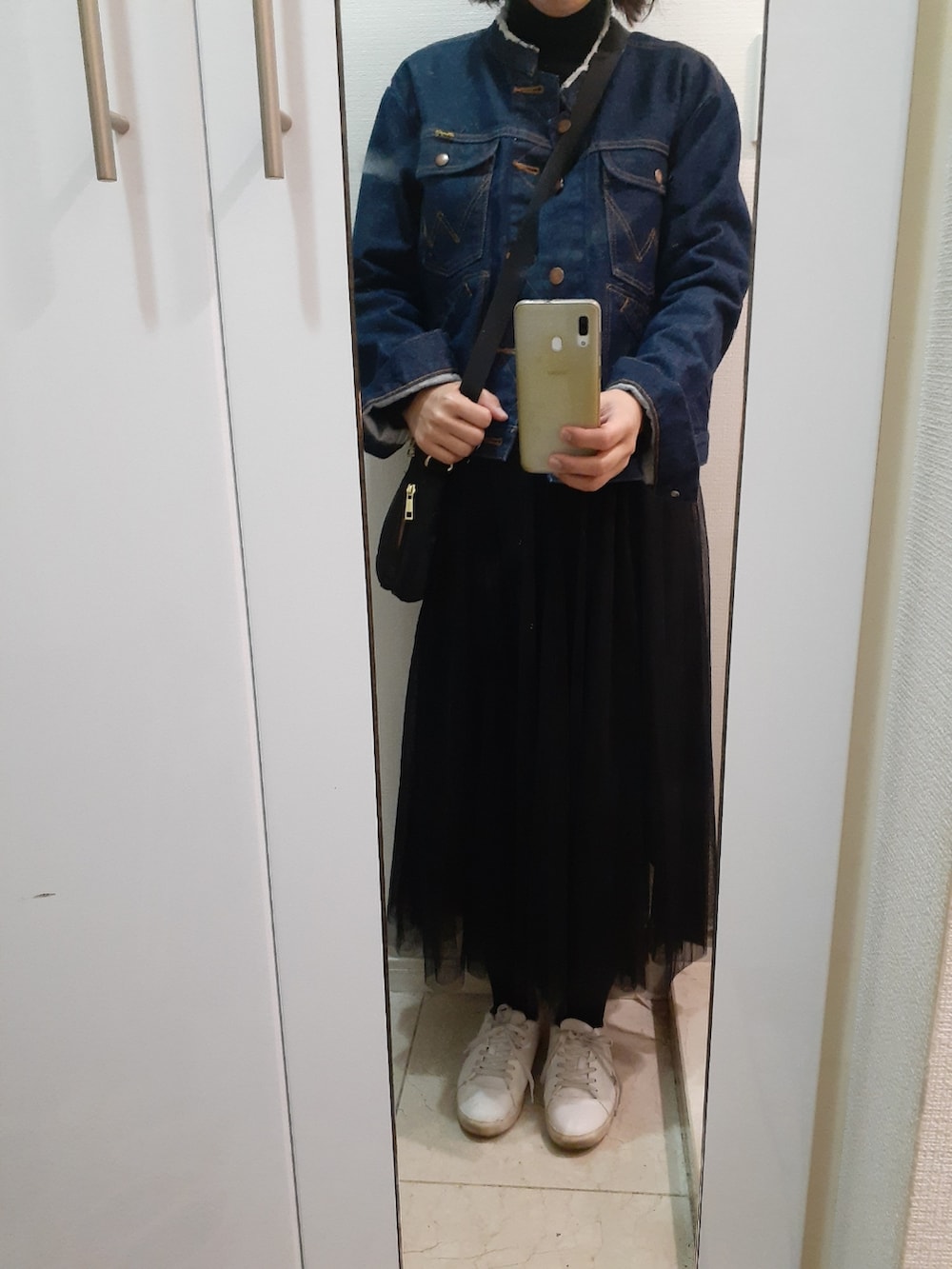 ホワイト系のスニーカー、ブラック系のスカート、ブルー系のデニムジャケットを着用したレディースの春コーディネートの2枚目の写真