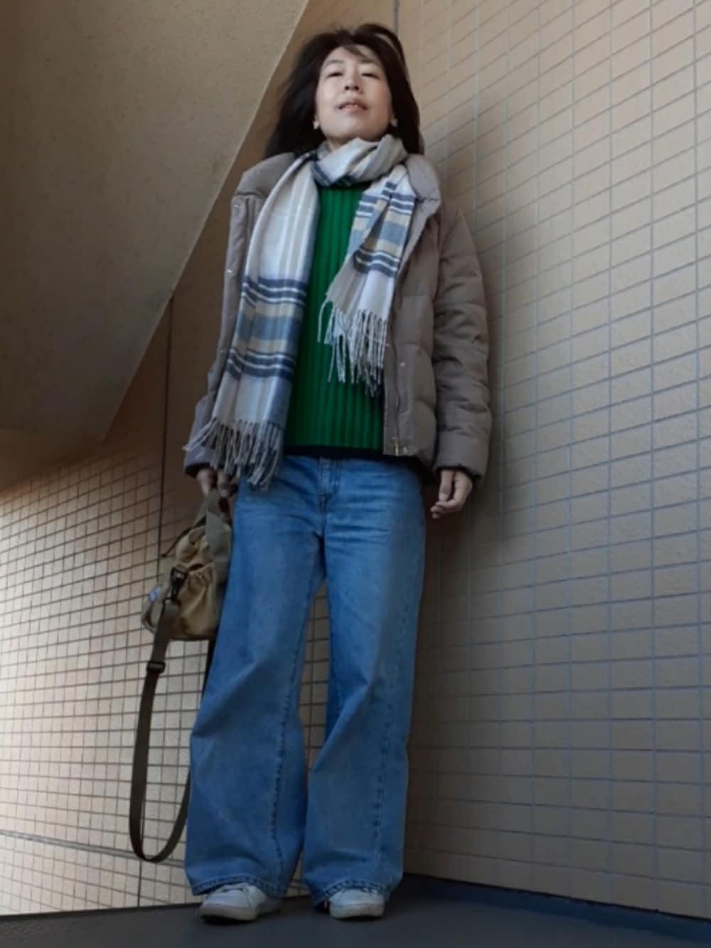 グリーン系のニット/セーター、ブルー系のデニムパンツ、ホワイト系のスニーカーを着用したレディースの春コーディネートの2枚目の写真