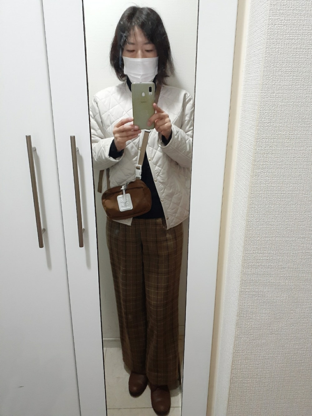ブラウン系のその他パンツ、ブラウン系のバッグ、ホワイト系のノーカラージャケットを着用したレディースの冬コーディネートの4枚目の写真