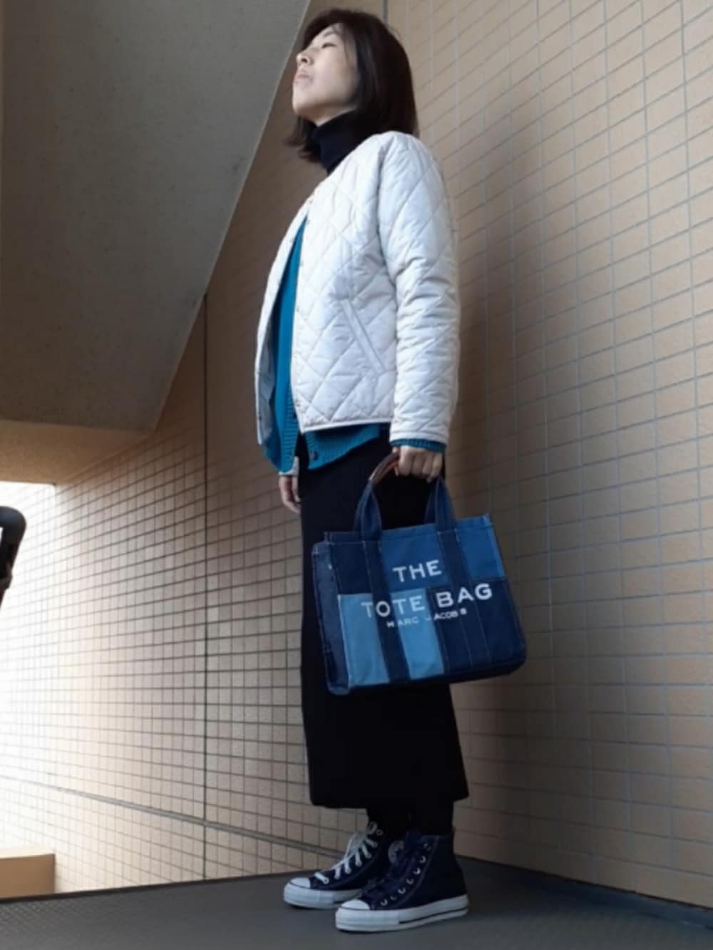 ブルー系のスニーカー、ブラック系のスカート、ホワイト系のノーカラージャケットを着用したレディースの冬コーディネートの3枚目の写真