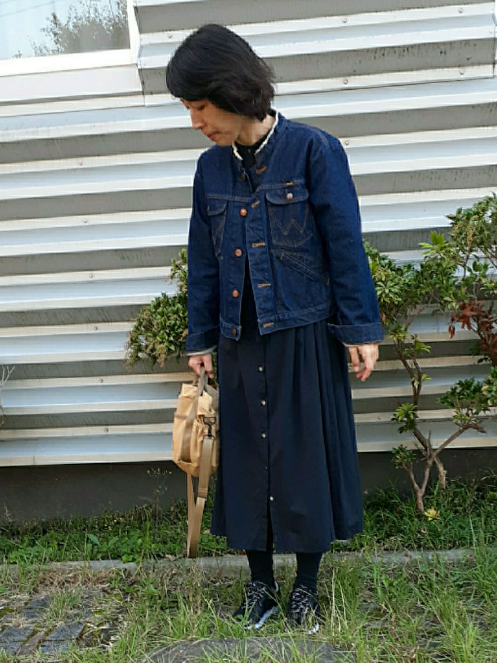 ベージュ系のショルダーバッグ、ブルー系のデニムジャケット、ブラック系のスニーカーを着用したレディースの秋コーディネートの2枚目の写真