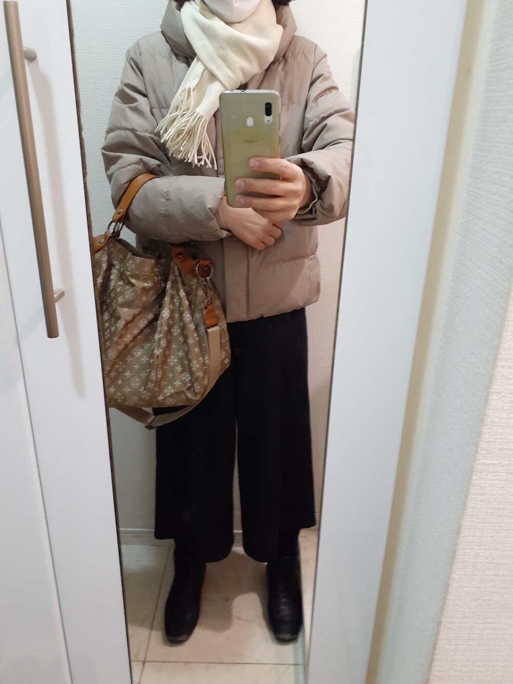 ブラウン系のバッグ、ベージュ系のダウンジャケット/コートを着用したレディースの冬コーディネートの2枚目の写真