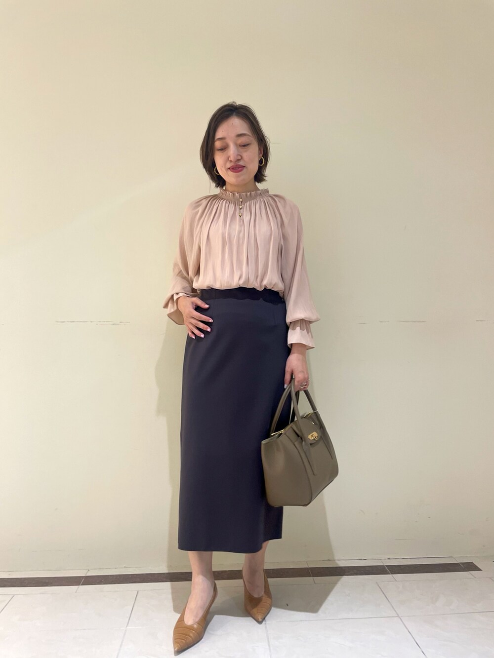 ホワイト系のスカート、ブラウン系のショルダーバッグ、イエロー系のシャツ/ブラウスを着用したレディースの秋コーディネートの3枚目の写真