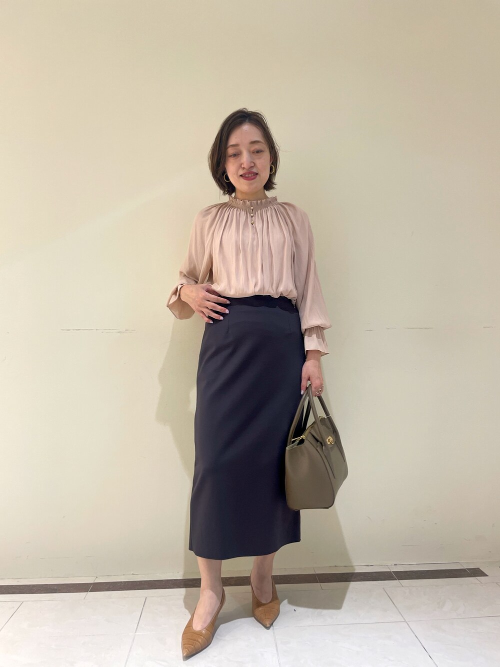 ホワイト系のスカート、ブラウン系のショルダーバッグ、イエロー系のシャツ/ブラウスを着用したレディースの秋コーディネートの2枚目の写真