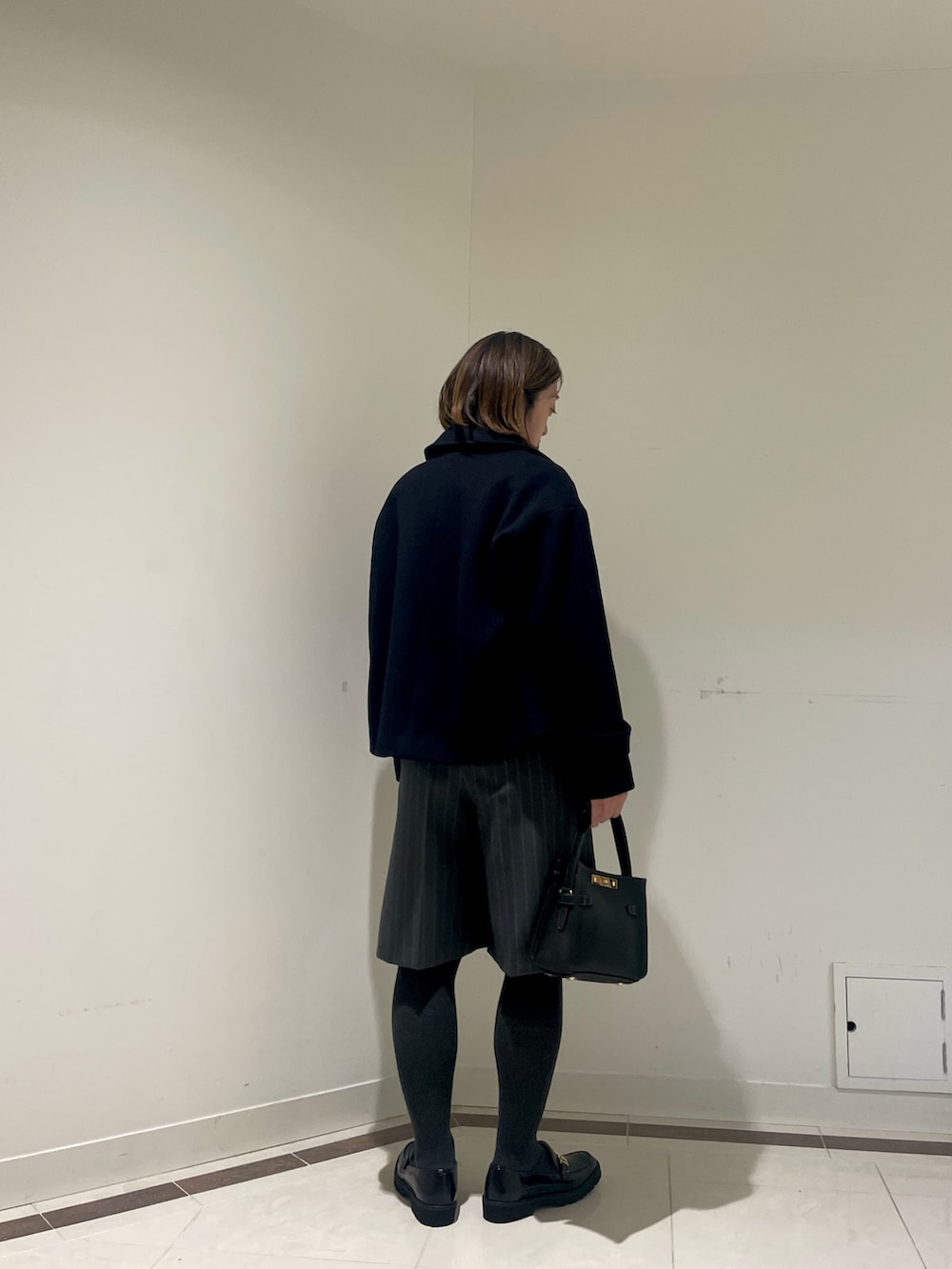 ブラック系のその他パンツ、ブルー系のピーコート、ピンク系のカーディガン/ボレロを着用したレディースの冬コーディネートの3枚目の写真