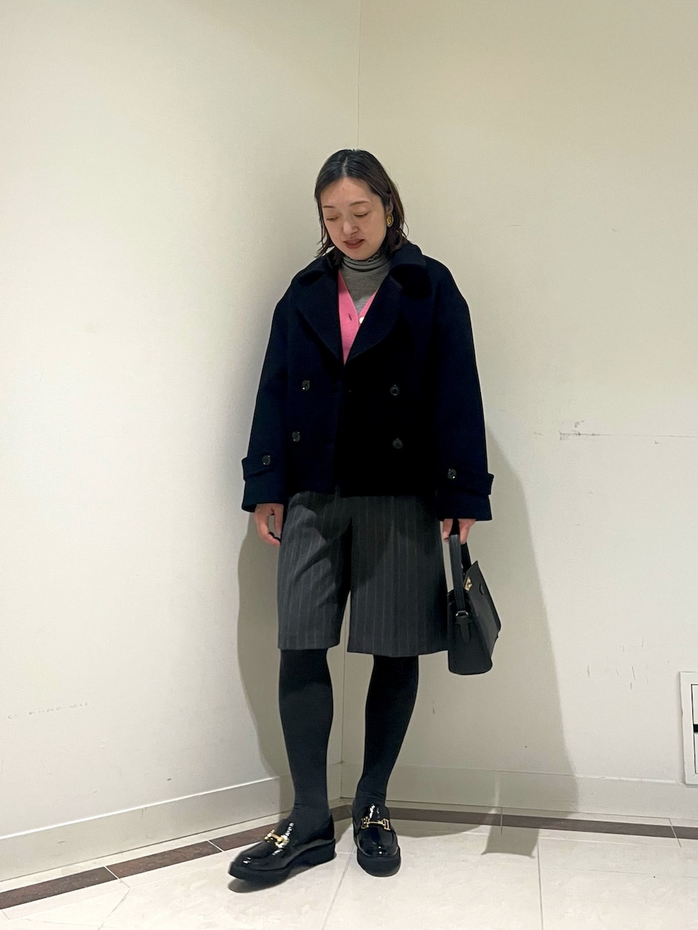 ブラック系のその他パンツ、ブルー系のピーコート、ピンク系のカーディガン/ボレロを着用したレディースの冬コーディネートの2枚目の写真