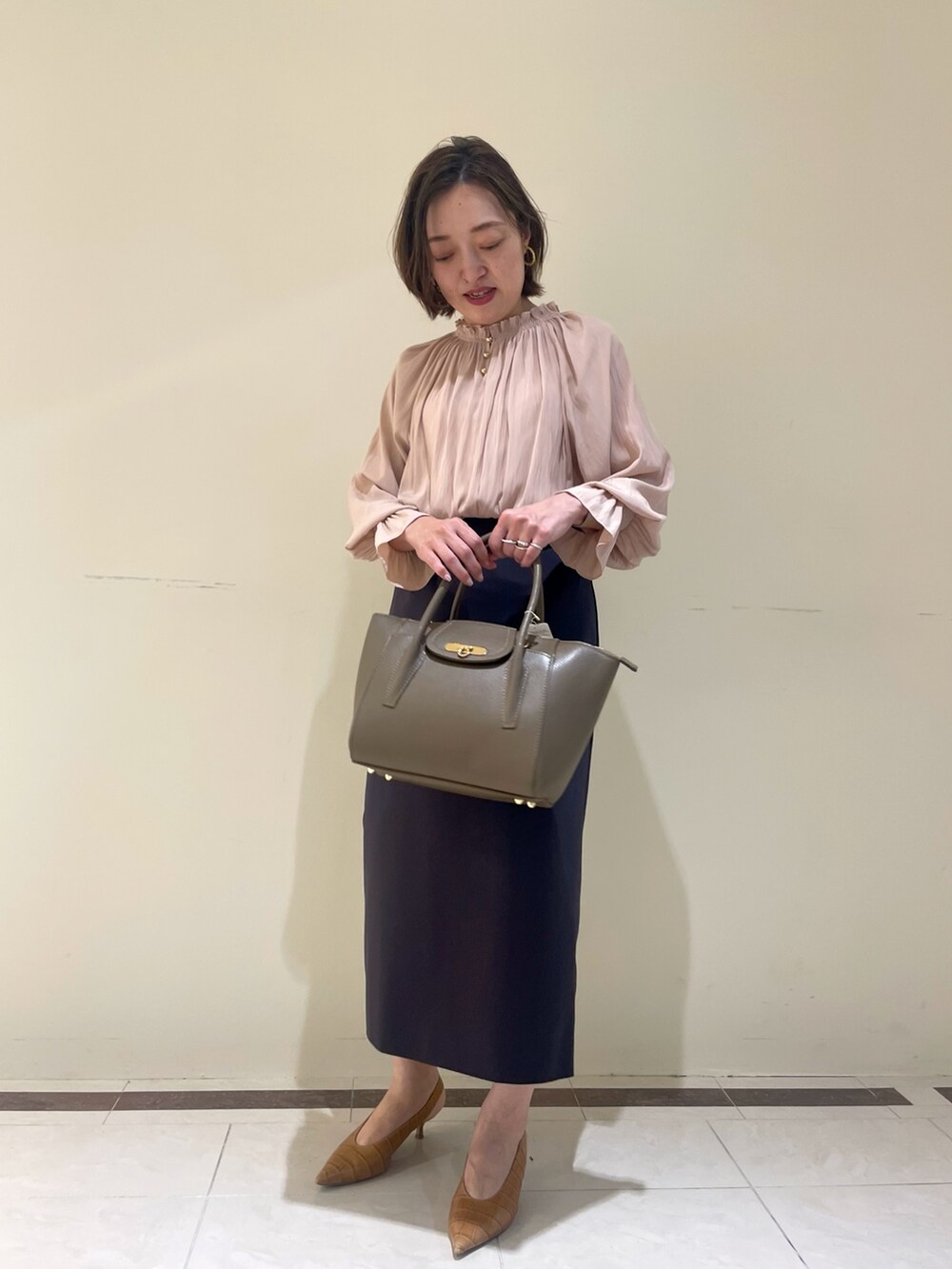 ホワイト系のスカート、ブラウン系のショルダーバッグ、イエロー系のシャツ/ブラウスを着用したレディースの秋コーディネートの6枚目の写真