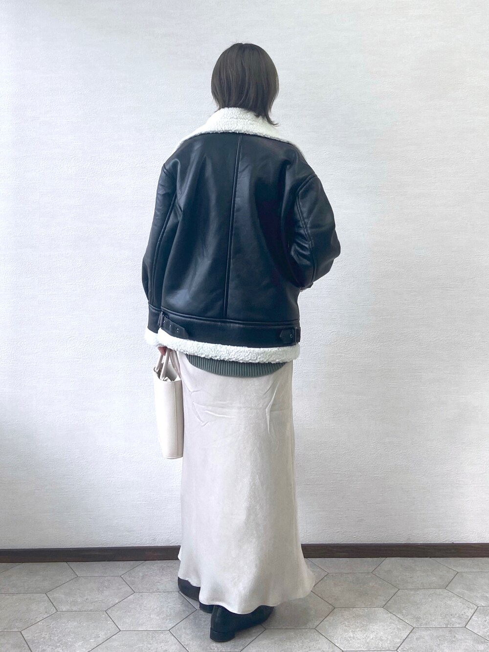 ブラック系のブルゾン、ホワイト系のショルダーバッグ、グリーン系のニット/セーターを着用したレディースの冬コーディネートの3枚目の写真