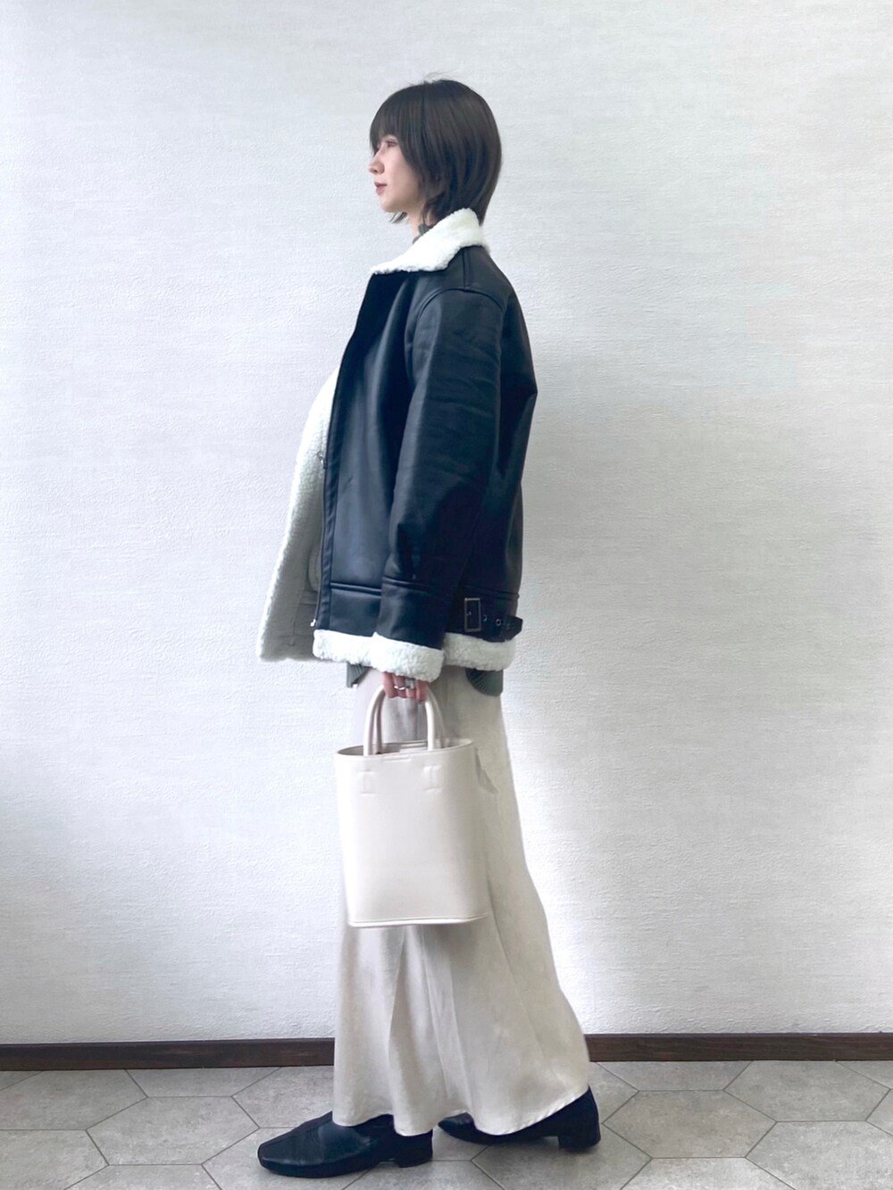 ブラック系のブルゾン、ホワイト系のショルダーバッグ、グリーン系のニット/セーターを着用したレディースの冬コーディネートの2枚目の写真