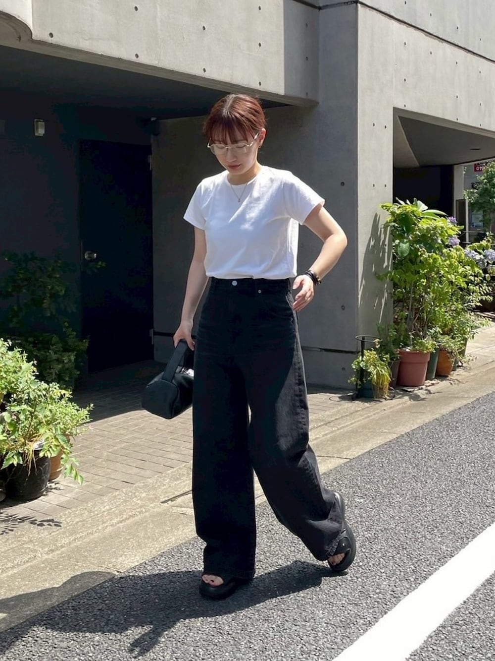 ブラック系のデニムパンツを着用したレディースの夏コーディネートの2枚目の写真