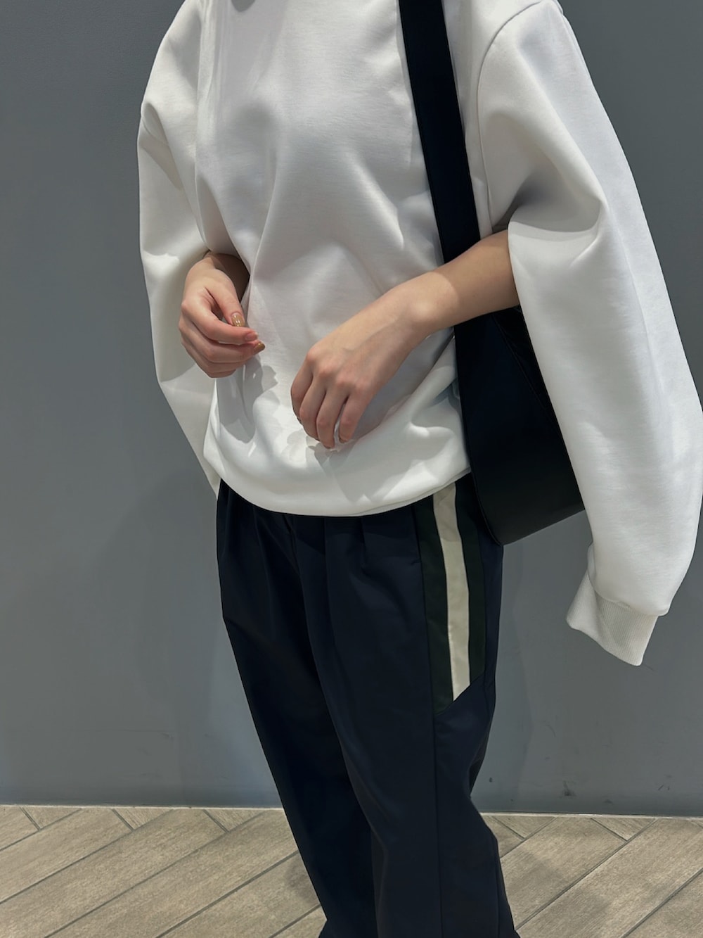 ホワイト系のスウェット、ブラック系のスラックスを着用したレディースの春コーディネートの2枚目の写真