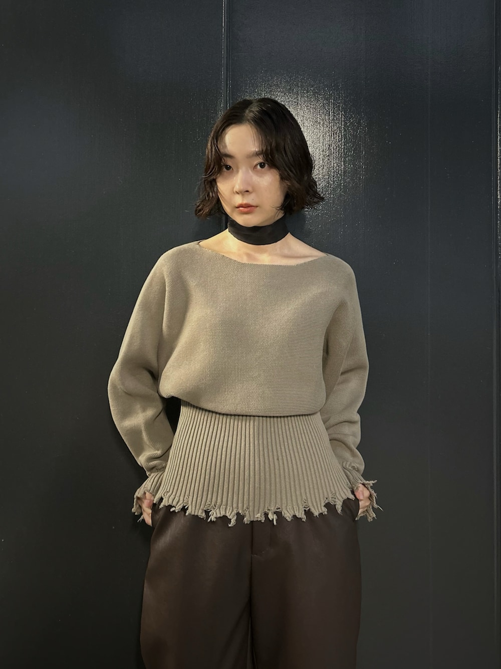 ベージュ系のニット/セーター、ブラウン系のスラックス、ブラック系のバンダナ/スカーフを着用したレディースの秋コーディネートの2枚目の写真