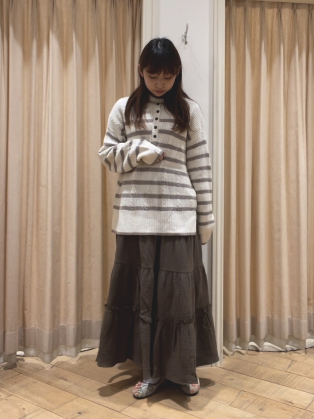 ベージュ系のニット/セーター、ベージュ系のカーディガン/ボレロ、グリーン系のスカートを着用したレディースの冬コーディネートの2枚目の写真