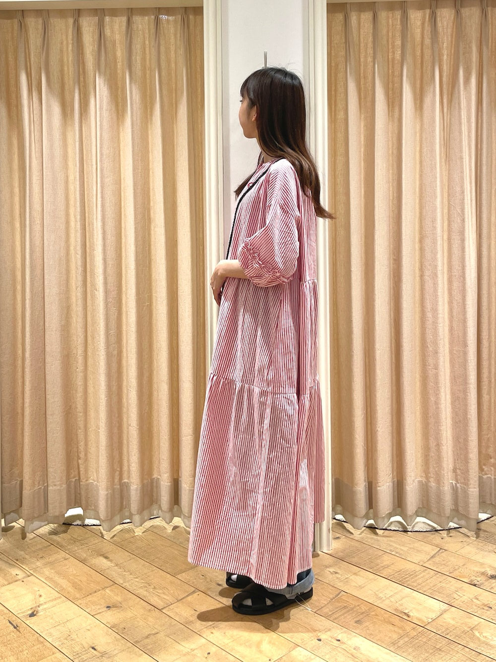 ブラック系のサンダル、ブラック系のハンドバッグ、レッド系のワンピースを着用したレディースの春コーディネートの2枚目の写真