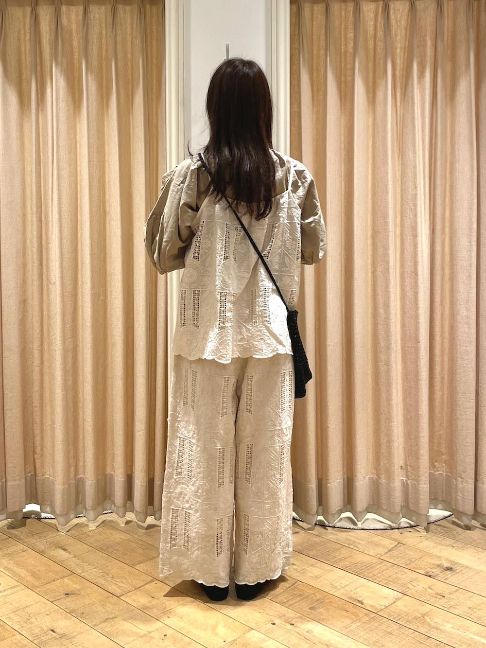 ブラック系のハンドバッグ、ブラック系のドレスシューズ、ベージュ系のシャツ/ブラウスを着用したレディースの春コーディネートの3枚目の写真