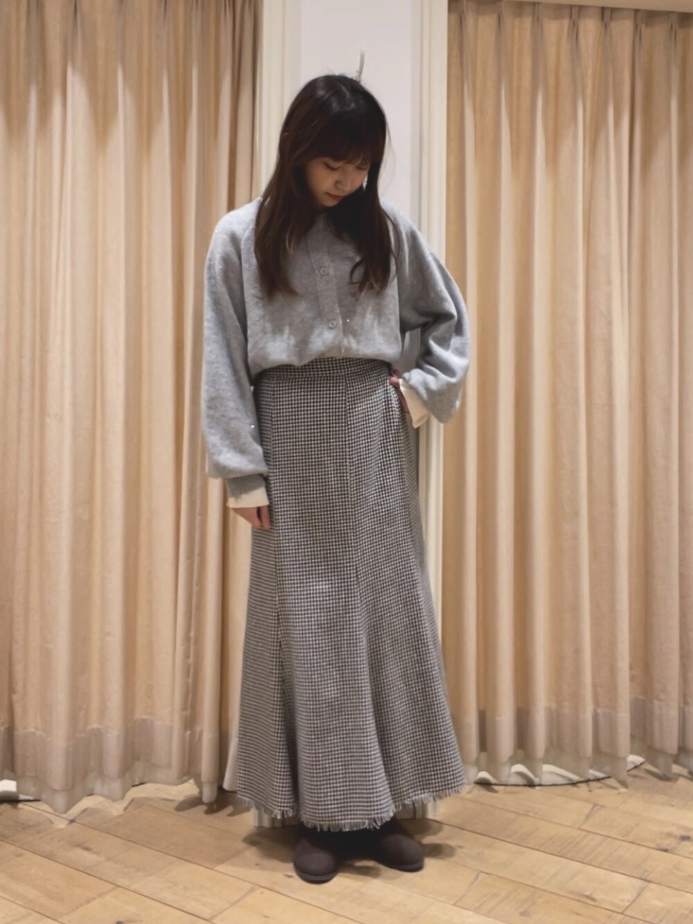 グレー系のカーディガン/ボレロ、ホワイト系のTシャツ/カットソー、ホワイト系のスカートを着用したレディースの冬コーディネートの2枚目の写真