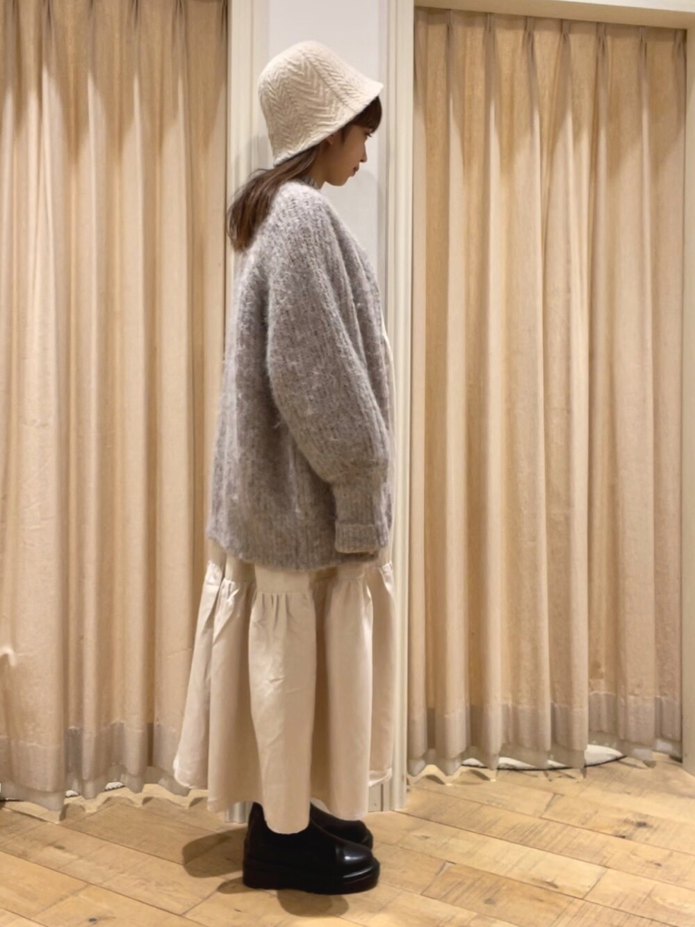 ブラック系のブーツ、ブラウン系のカーディガン/ボレロ、グレー系のシャツ/ブラウスを着用したレディースの秋コーディネートの2枚目の写真