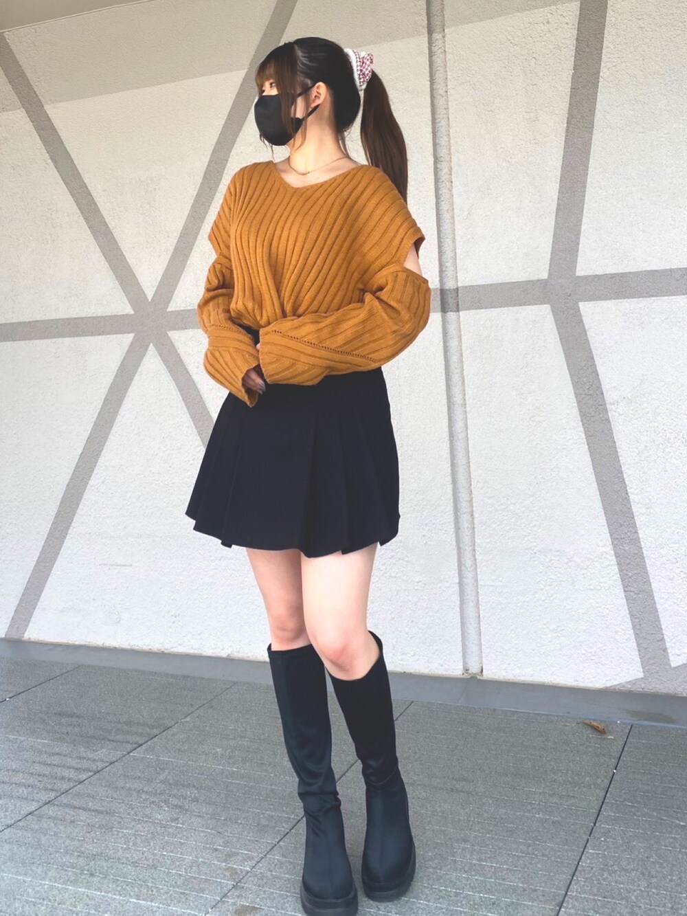 ブラウン系のニット/セーター、ブラック系のスカート、ブラック系のブーツを着用したレディースの春コーディネートの2枚目の写真