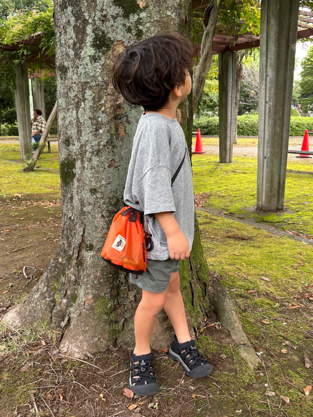 ブラック系のサンダル、グレー系のTシャツ/カットソー、オレンジ系のショルダーバッグを着用したキッズの秋コーディネートの2枚目の写真