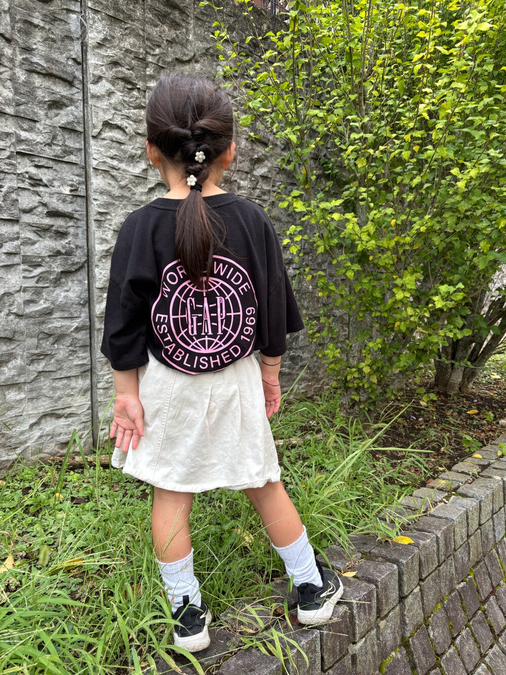 ブラック系のTシャツ/カットソー、ホワイト系のスカート、ブラック系のスニーカーを着用したキッズの秋コーディネートの2枚目の写真