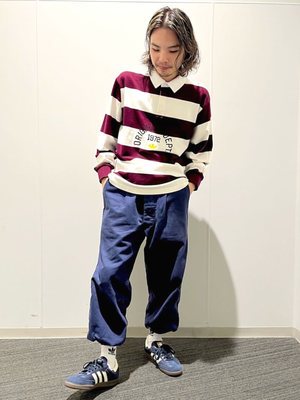 ホワイト系のポロシャツ、ブルー系のスニーカーを着用したメンズの秋コーディネートの2枚目の写真