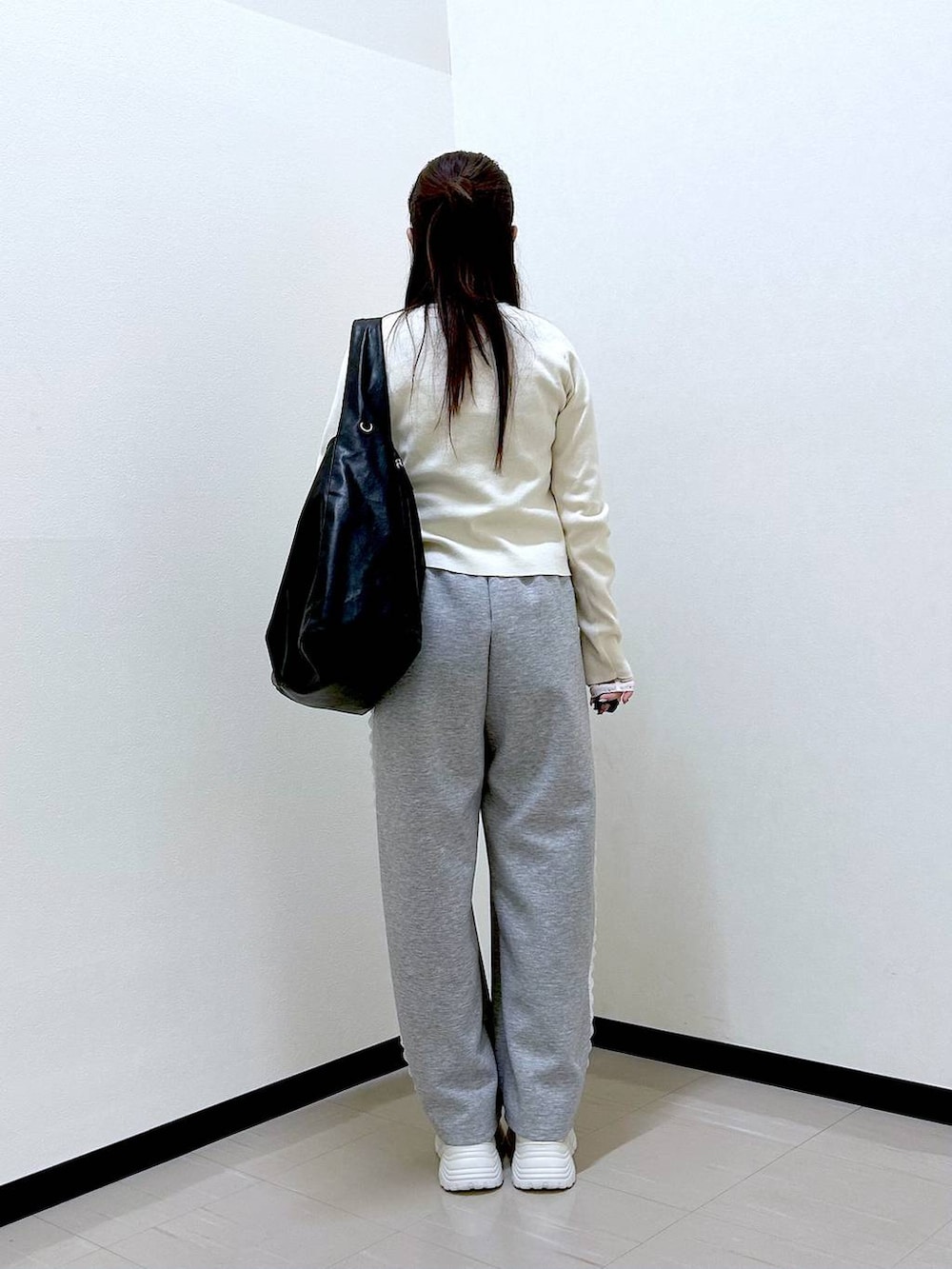 グレー系のスウェットパンツ、ホワイト系のTシャツ/カットソー、ホワイト系のスニーカーを着用したレディースの冬コーディネートの4枚目の写真