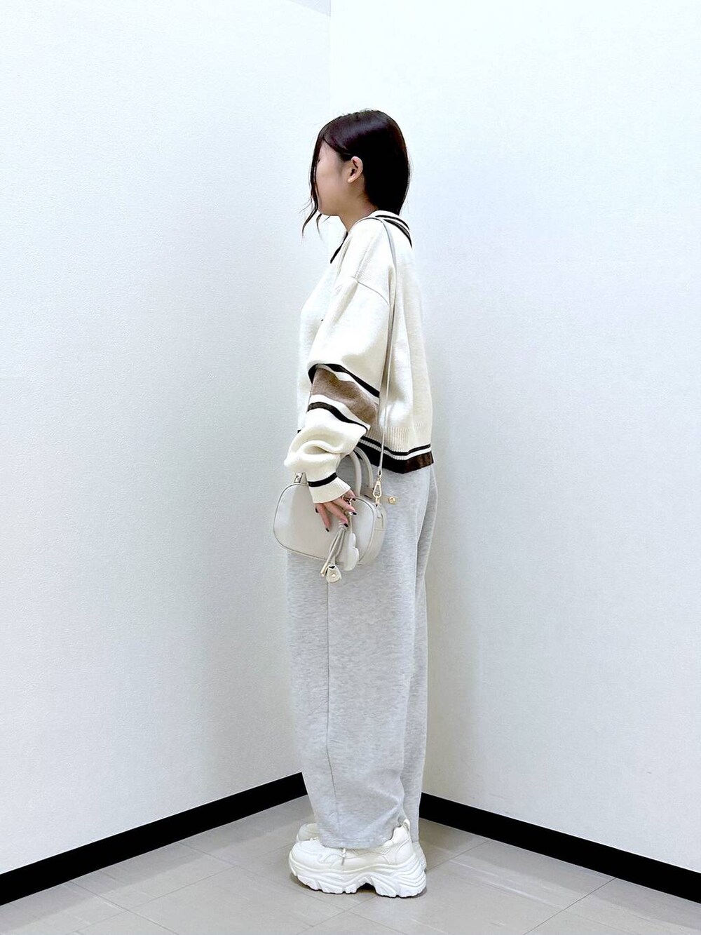 グレー系のスウェットパンツ、ホワイト系のボストンバッグ、ホワイト系のニット/セーターを着用したレディースの冬コーディネートの3枚目の写真