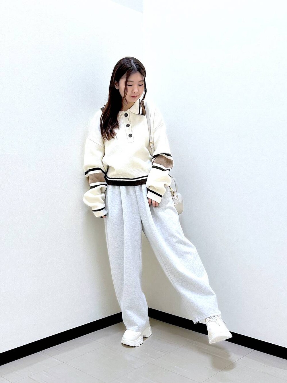 グレー系のスウェットパンツ、ホワイト系のボストンバッグ、ホワイト系のニット/セーターを着用したレディースの冬コーディネートの2枚目の写真