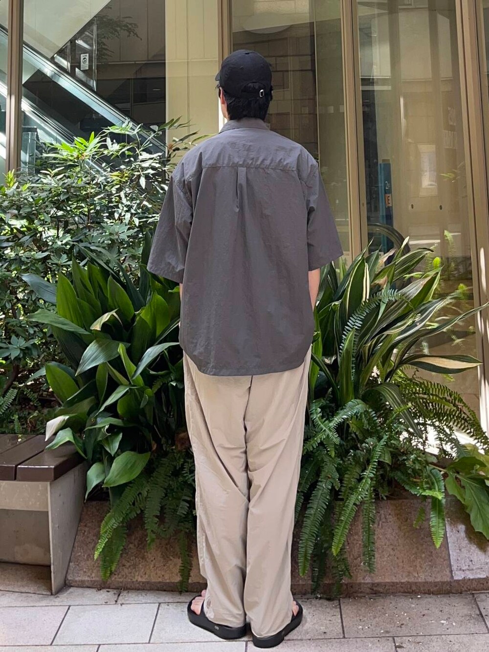 グレー系のその他パンツ、ブラック系のサンダル、ホワイト系のTシャツ/カットソーを着用したメンズの夏コーディネートの2枚目の写真