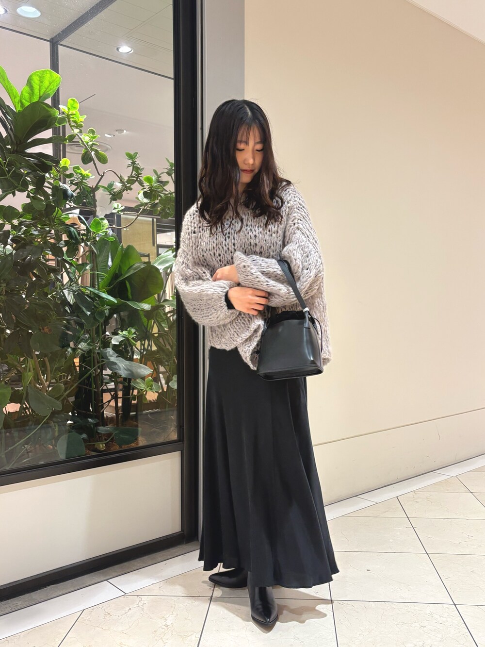 グレー系のニット/セーター、ブラック系のスカート、ブラック系のハンドバッグを着用したレディースの秋コーディネートの3枚目の写真