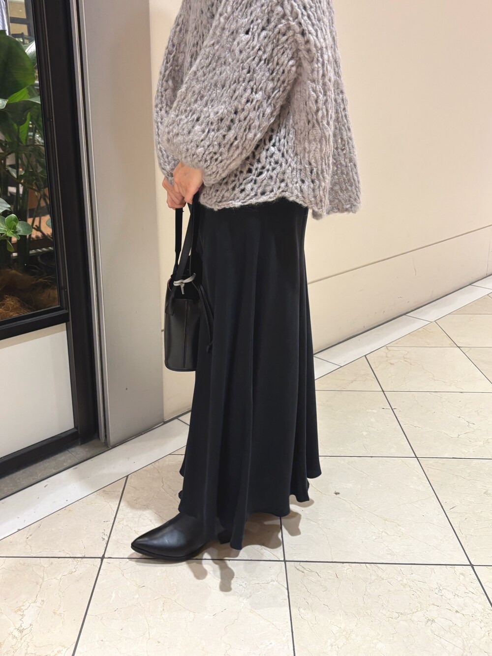 グレー系のニット/セーター、ブラック系のスカート、ブラック系のハンドバッグを着用したレディースの秋コーディネートの5枚目の写真