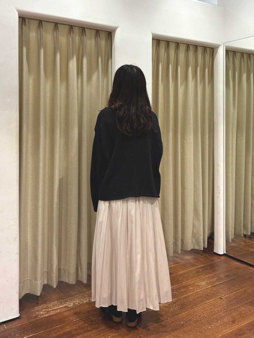 ホワイト系のスカート、ブラック系のサンダル、ブラック系のニット/セーターを着用したレディースの秋コーディネートの3枚目の写真