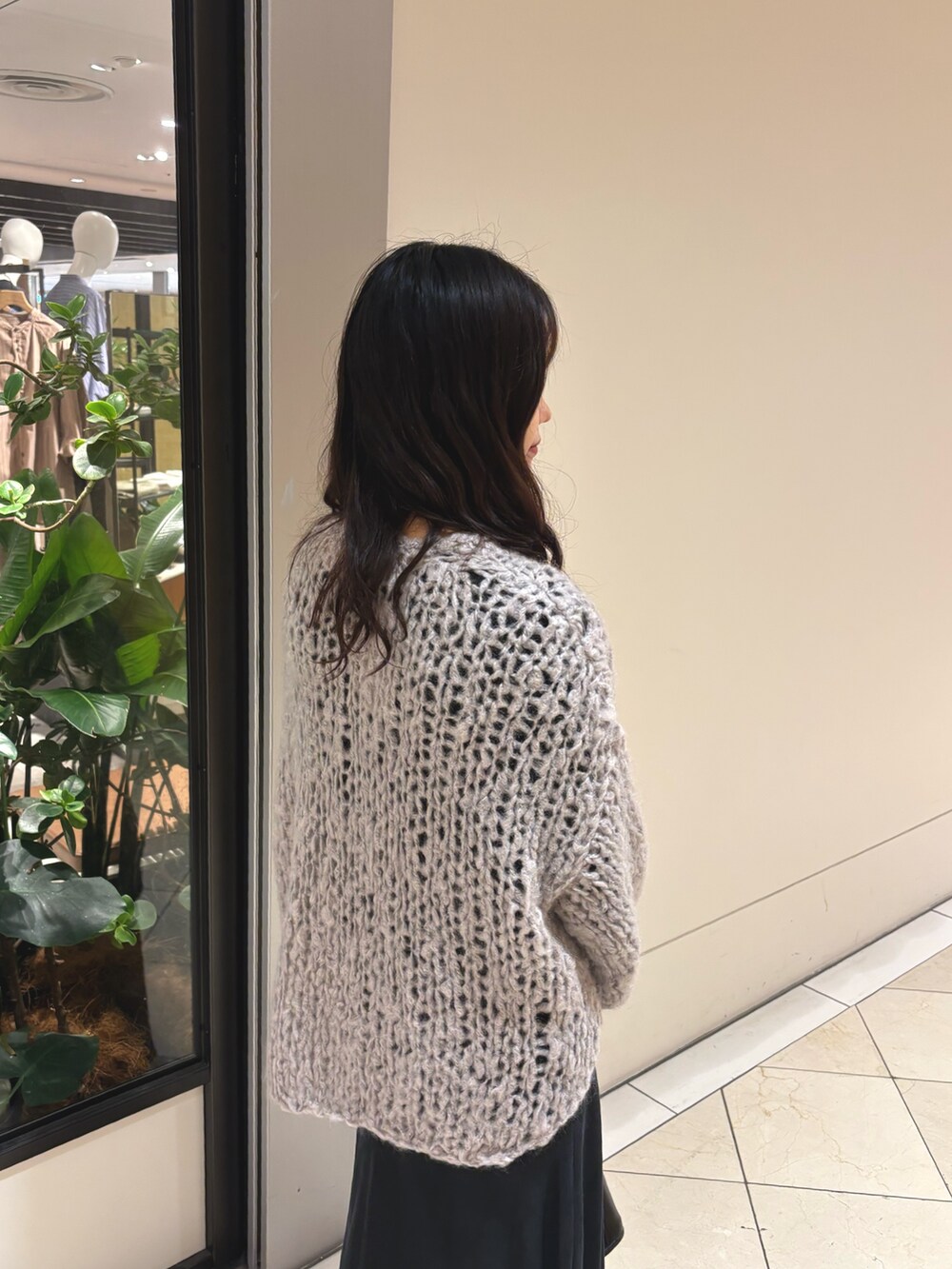 グレー系のニット/セーター、ブラック系のスカート、ブラック系のハンドバッグを着用したレディースの秋コーディネートの4枚目の写真