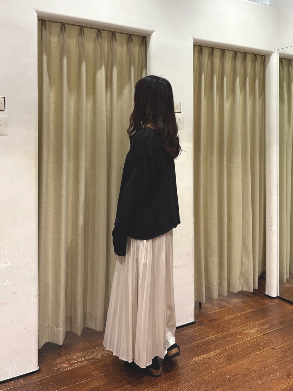 ホワイト系のスカート、ブラック系のサンダル、ブラック系のニット/セーターを着用したレディースの秋コーディネートの2枚目の写真