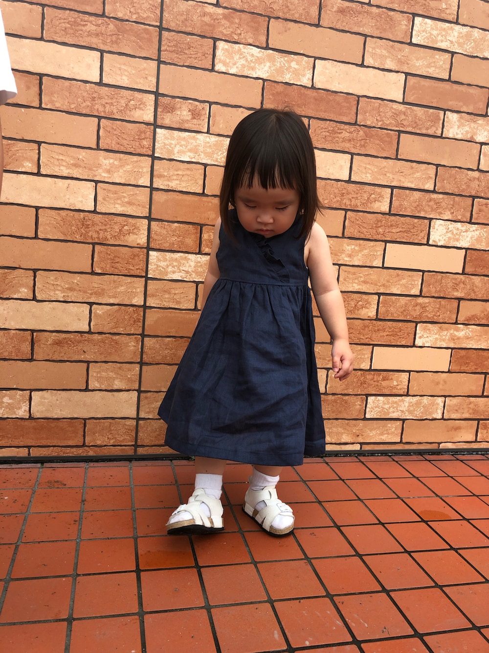 ブラック系のワンピース、ホワイト系のサンダル、ホワイト系のシャツ/ブラウスを着用したキッズの秋コーディネートの3枚目の写真