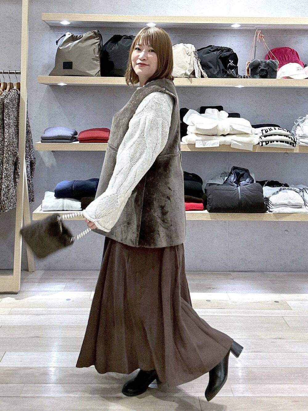 グレー系のニット/セーター、ブラック系のブーツ、グレー系のショルダーバッグを着用したレディースの冬コーディネートの4枚目の写真