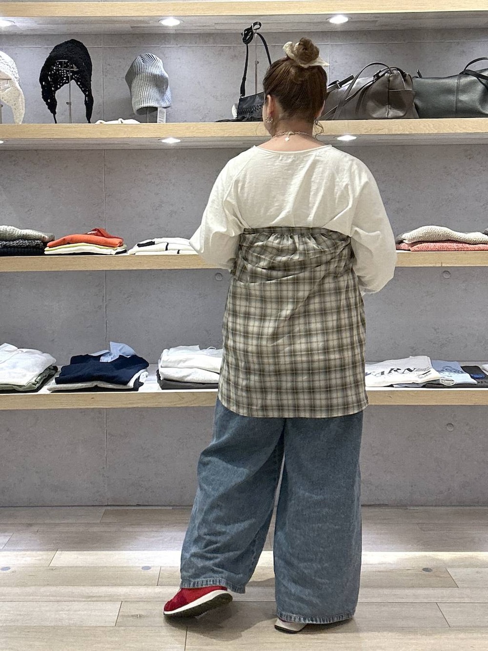 ブルー系のデニムパンツ、レッド系のスニーカー、ホワイト系のTシャツ/カットソーを着用したレディースの春コーディネートの2枚目の写真