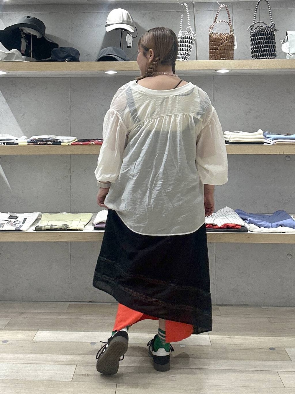 オレンジ系のスカート、ブラック系のワンピース、ベージュ系のシャツ/ブラウスを着用したレディースの夏コーディネートの2枚目の写真