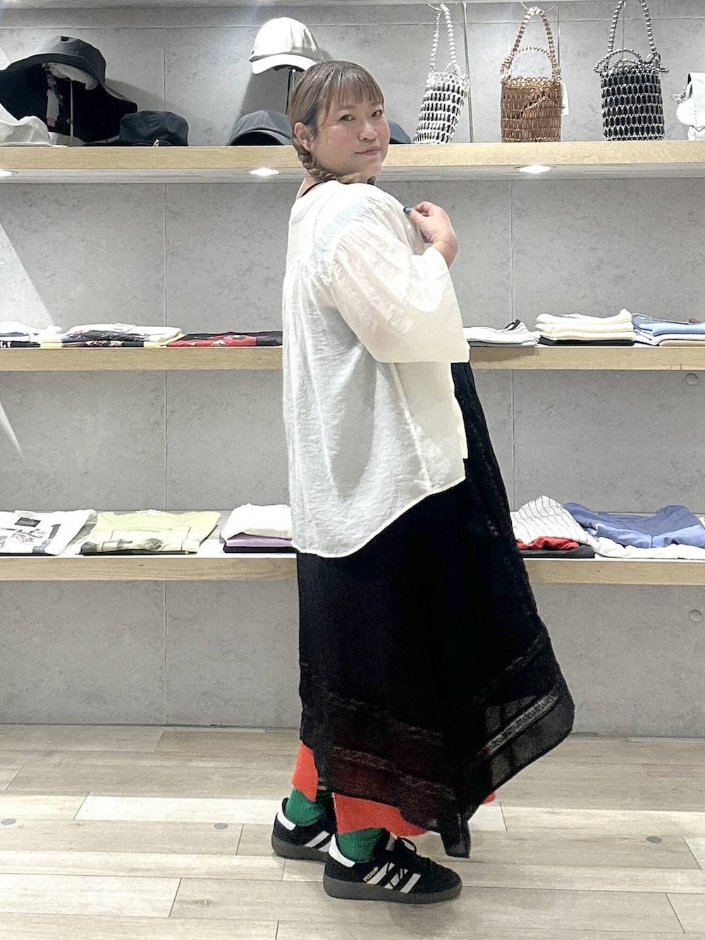 オレンジ系のスカート、ブラック系のワンピース、ベージュ系のシャツ/ブラウスを着用したレディースの夏コーディネートの3枚目の写真