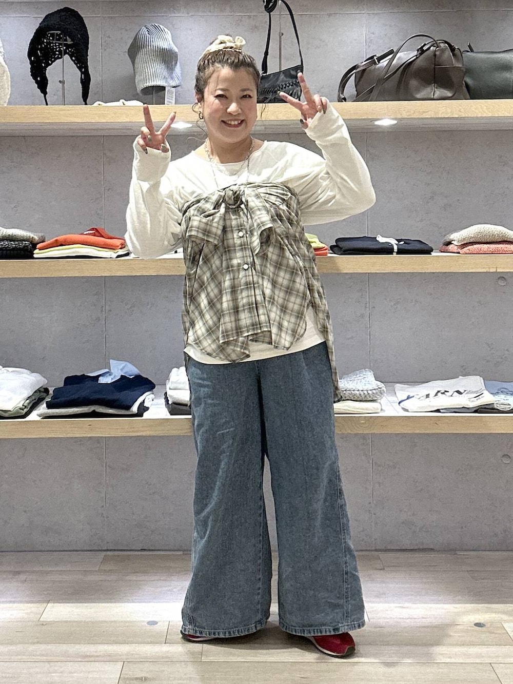 ブルー系のデニムパンツ、レッド系のスニーカー、ホワイト系のTシャツ/カットソーを着用したレディースの春コーディネートの6枚目の写真