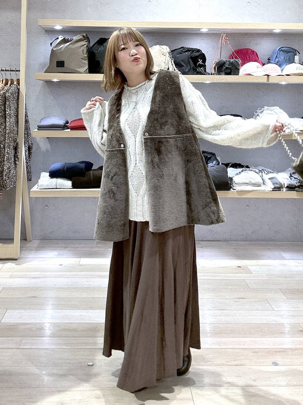 グレー系のニット/セーター、ブラック系のブーツ、グレー系のショルダーバッグを着用したレディースの冬コーディネートの6枚目の写真